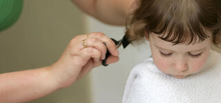 Mutter schneidt Kind die Haare