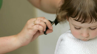 Mutter schneidt Kind die Haare