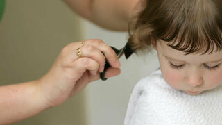 Mutter schneidt Kind die Haare