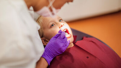 Eine Zahnärztin kontrolliert die Zähne eines Jungen.