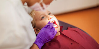 Eine Zahnärztin kontrolliert die Zähne eines Jungen.