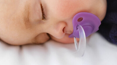Baby schläft mit Schnuller im Mund