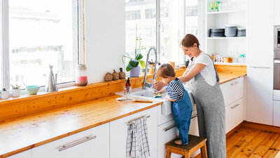 Mutter und Kleinkind in der Küche beim Abwaschen