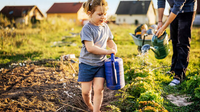 Girl with the watering can in a vegetable field