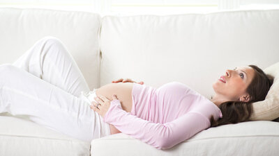 Schwangere liegt auf dem Sofa