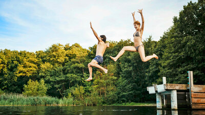 Paar springt vom Steg in einen See