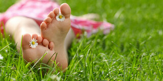 Frau liegt mit bloßen Füßen im Gras