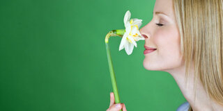 Frau riecht an Blume