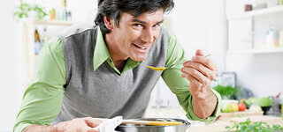 Mann schmeckt Suppe ab