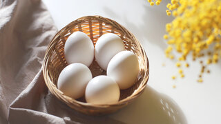 Fünf Eier liegen in einem Körbchen aus Bast.