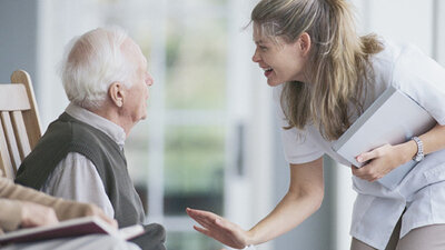 Senior unterhält sich mit Pflegekraft 