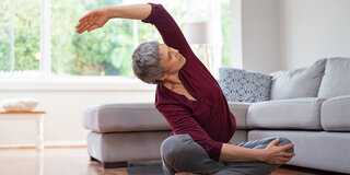 Seniorin macht Yoga im Wohnzimmer