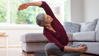 Seniorin macht Yoga im Wohnzimmer