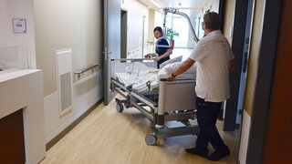 Medizinisches Personal schiebt im Flur eines Krankenhauses ein Krankenbett
