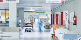Flur eines Krankenhauses mit leeren Krankenbetten und Personal