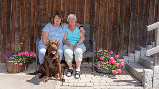 Maria Prepsel, 91, lebt in einer Pflege-Wohngemeinschaft in Happerg bei Wolfratshausen. Hauswirtschafterin Elisabeth (links) und Hofhund Chester sorgen für gute Laune.