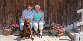 Maria Prepsel, 91, lebt in einer Pflege-Wohngemeinschaft in Happerg. Hauswirtschafterin Elisabeth (links) und Hofhund Chester sorgen für gute Laune.