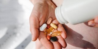 Tabletten werden aus einer Dose in eine Hand geschüttet
