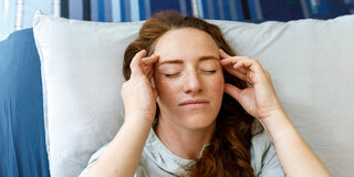 Ins Bett legen und ruhen: Das kann Kopfschmerzen lindern.