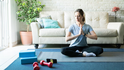Meditieren Meditation per App Frau Wohnzimmer Sofa Entspannen zuhören Ausprobieren Besinnung Teppich Matte Hanteln