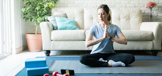 Meditieren Meditation per App Frau Wohnzimmer Sofa Entspannen zuhören Ausprobieren Besinnung Teppich Matte Hanteln