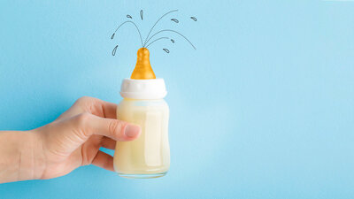 Eine Illustration zeigt ein Baby-Fläschen, aus dem einige Spritzer Milch herausspritzen.