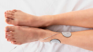 Am Unterschenkel einer Frau sind zwei Elektroden aufgeklebt.