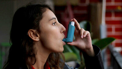 Eine Frau inhaliert mit einem Asthmaspray.