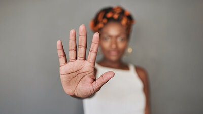 Eine Frau hält eine Hand abwehrend vor sich und signalisiert damit: Stopp!