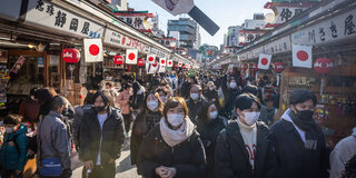 Mehrere Menschen gehen in Japan mit Mundschutz auf einer Straße