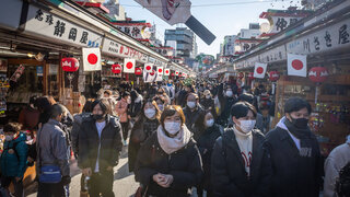 Mehrere Menschen gehen in Japan mit Mundschutz auf einer Straße