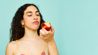 Eine Frau kaut bewusst einen Bissen von einem Apfel.