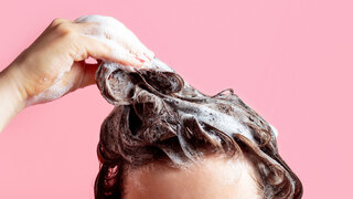 Ein Mensch schäumt sich die Haare mit Shampoo ein.