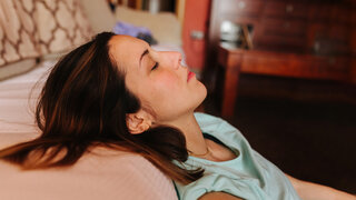 Eine Frau liegt mit geschlossenen Augen im Bett.