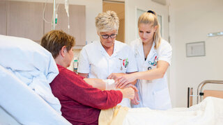 Zwei Pflegekräfte versorgen eine Patientin.