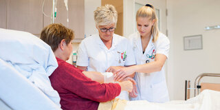 Zwei Pflegekräfte versorgen eine Patientin.
