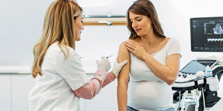Eine Ärztin impft eine schwangere Frau.