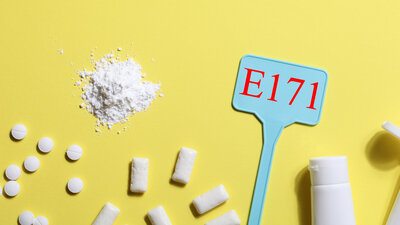 Eine Illustration zeigt Lebensmittel und Medikamente mit weißer Färbung durch Titandioxid, außerdem ein Schild mit der Aufschrift E171.