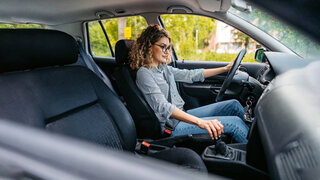Eine Frau sitzt auf einem Autositz hinter dem Steuer eines PKW.