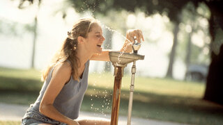 Eine Frau erfrischt sich mit Wasser.