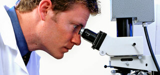 Mann schaut durch ein Mikroskop