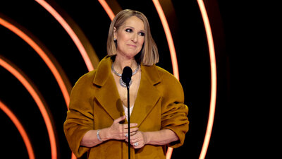 Die Sängerin Céline Dion steht vor einem Mikrofon und schaut nachdenklich.