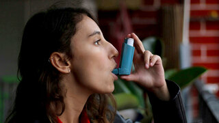 Frau inhaliert mit Asthmaspray
