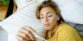 Frau mit Fieber im Bett