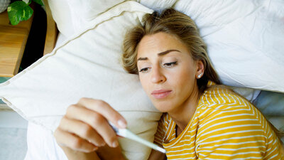 Frau mit Fieber im Bett