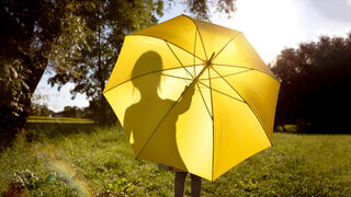 Parkszene mit gelbem Sonnenschirm.