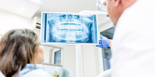 Zahnarzt zeigt Patientin Röntgenbild