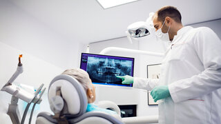 Zahnarzt zeigt Patientin Röntgenbild