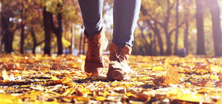 Coronavirus Winterblues Mit Bewegung gegensteuern Füße Close Herbst Blätter verwirbeln Gehen Stiefel Winterstiefel