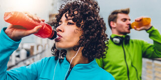 Wieviele müssen Sportler trinken Frau Mann Trinkflasche Rot Jogginganzug Trainingsjacke Jogger Locken Durst Wasserflasche Trinkflasche durstig Flüssigkeit